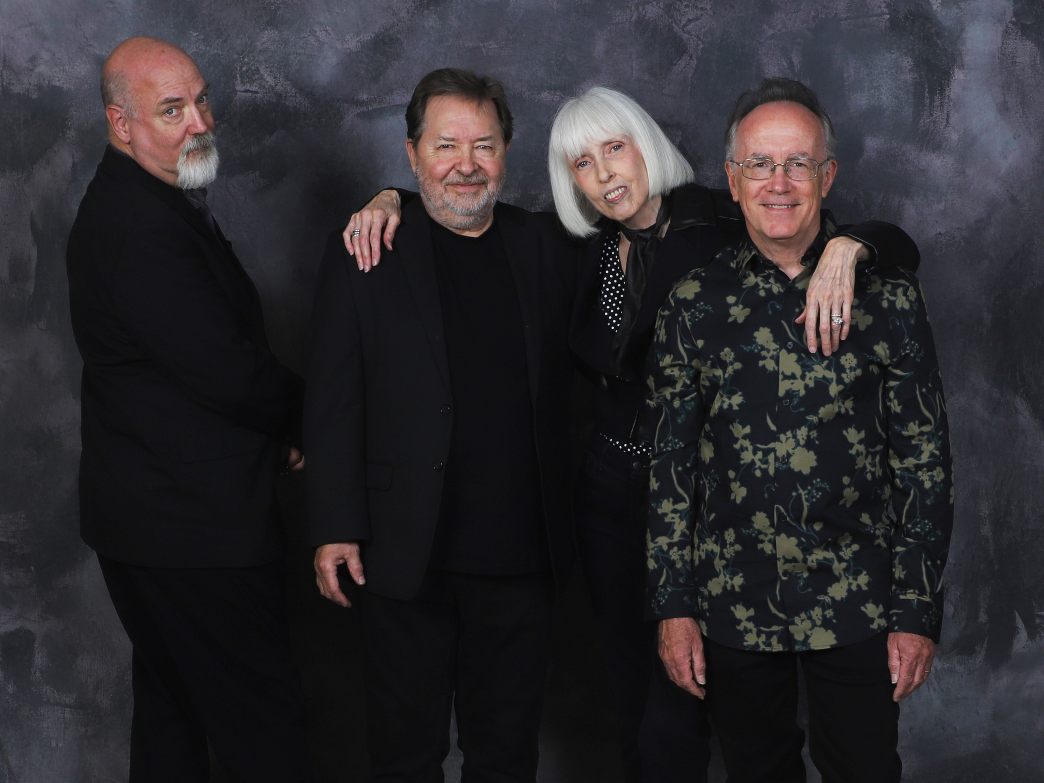 Rand Gardner, Bill Williams, Scott McKnight, Dede Wyland standing together in front of a dark grey background
