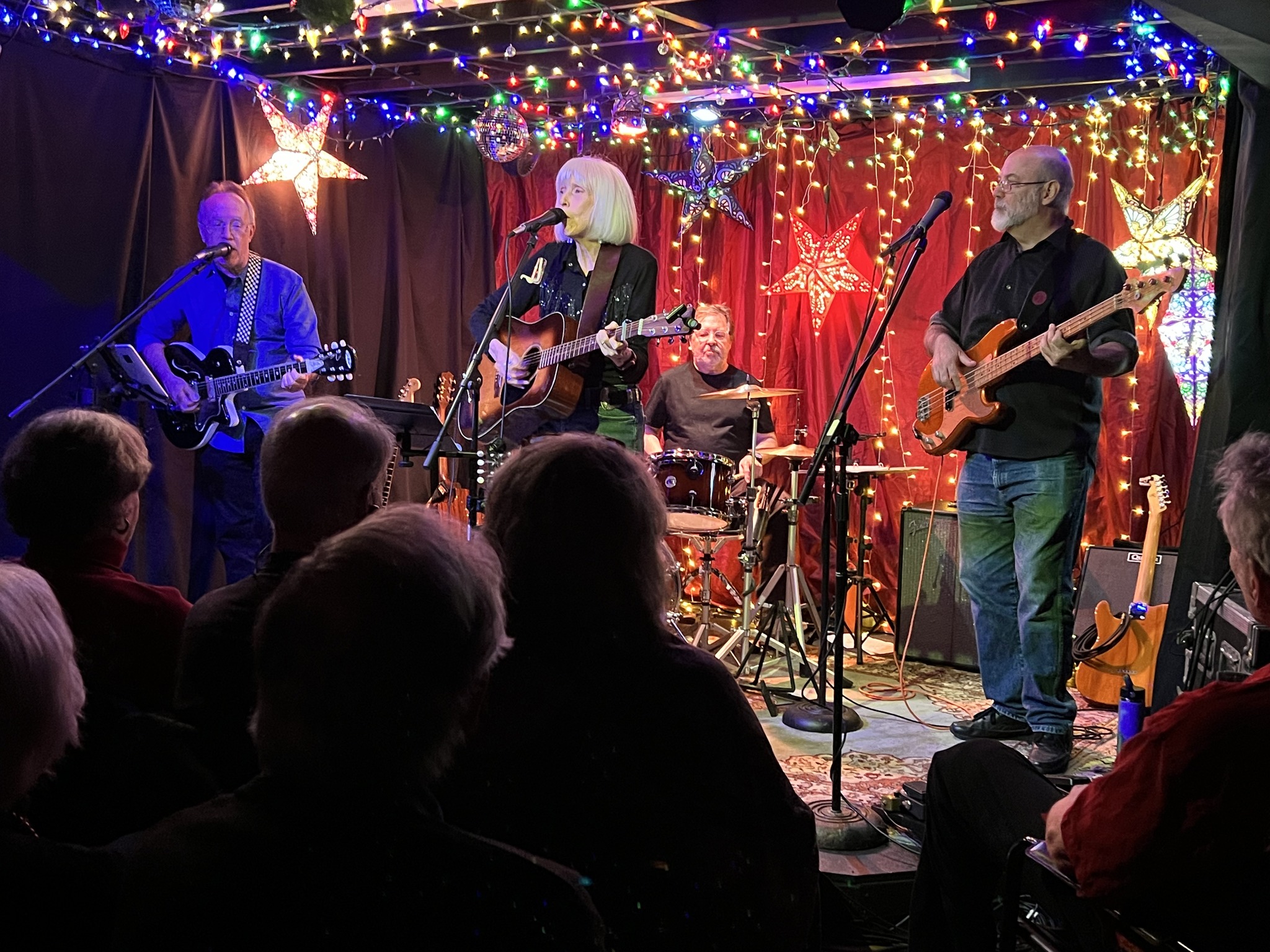 Rand Gardner, Bill Williams, Scott McKnight, Dede Wyland performing on stage under multicolored lights and a full audience